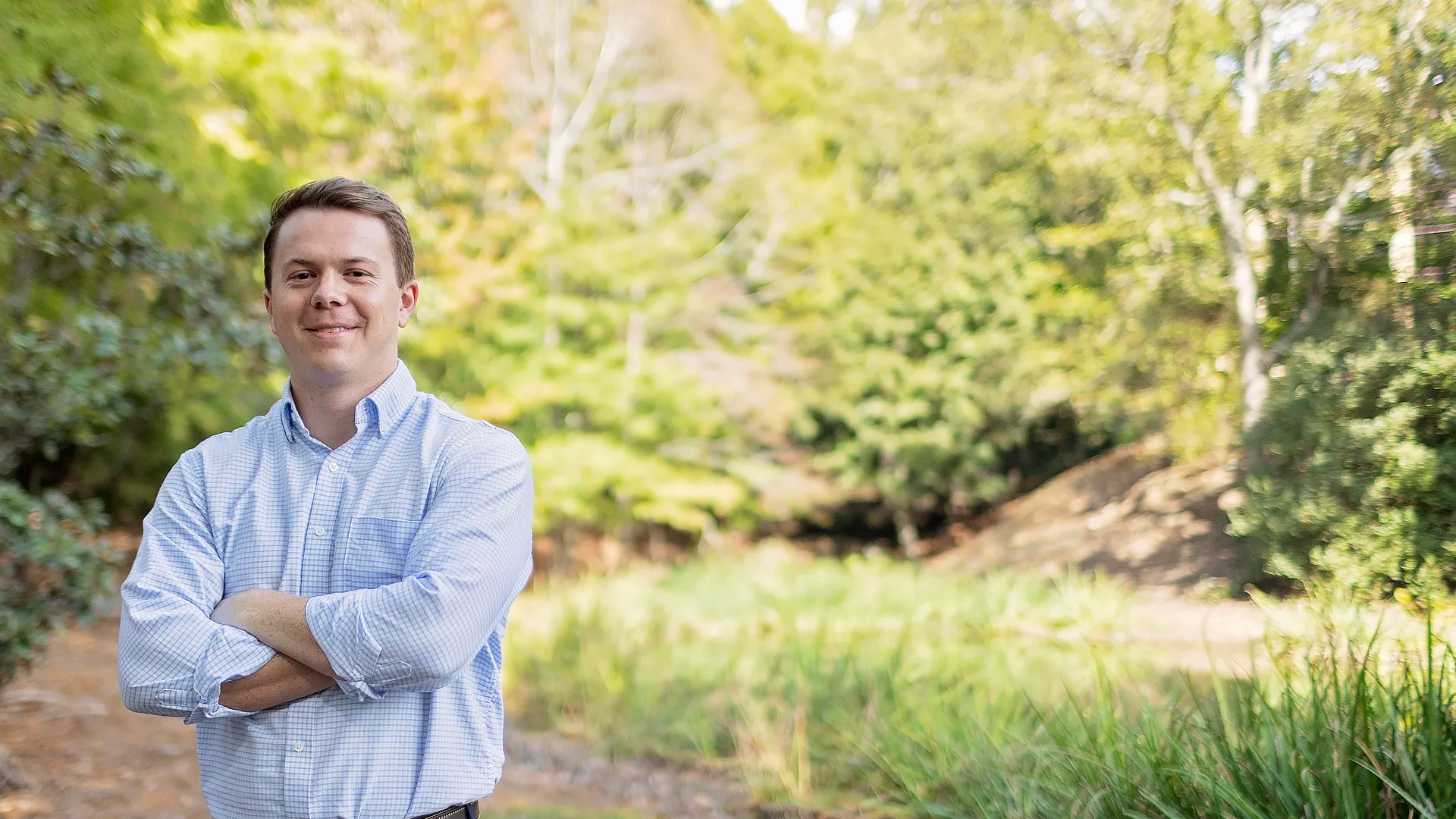 male student standing in the forest