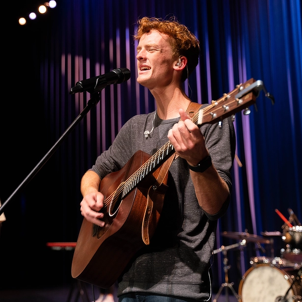 young man singing and playing guitar