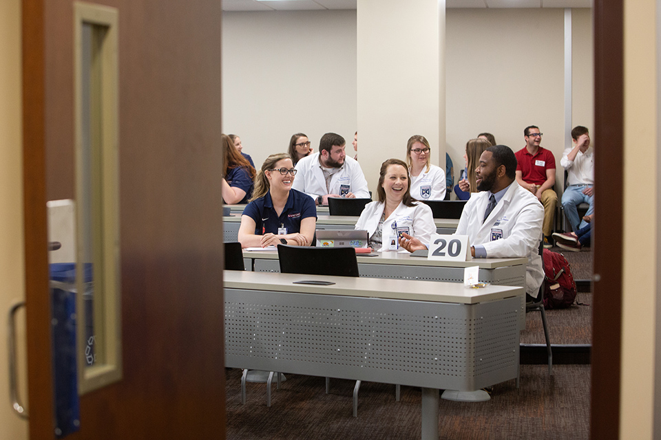 Two pharmacy students talk with a physical therapy student.