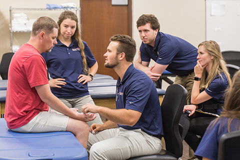 Male professor fitting electrodes on male student