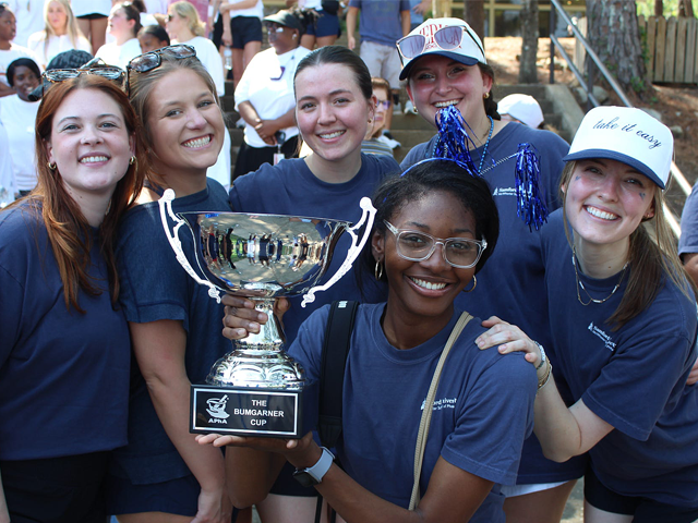 females wearing blue shirts holding trophy