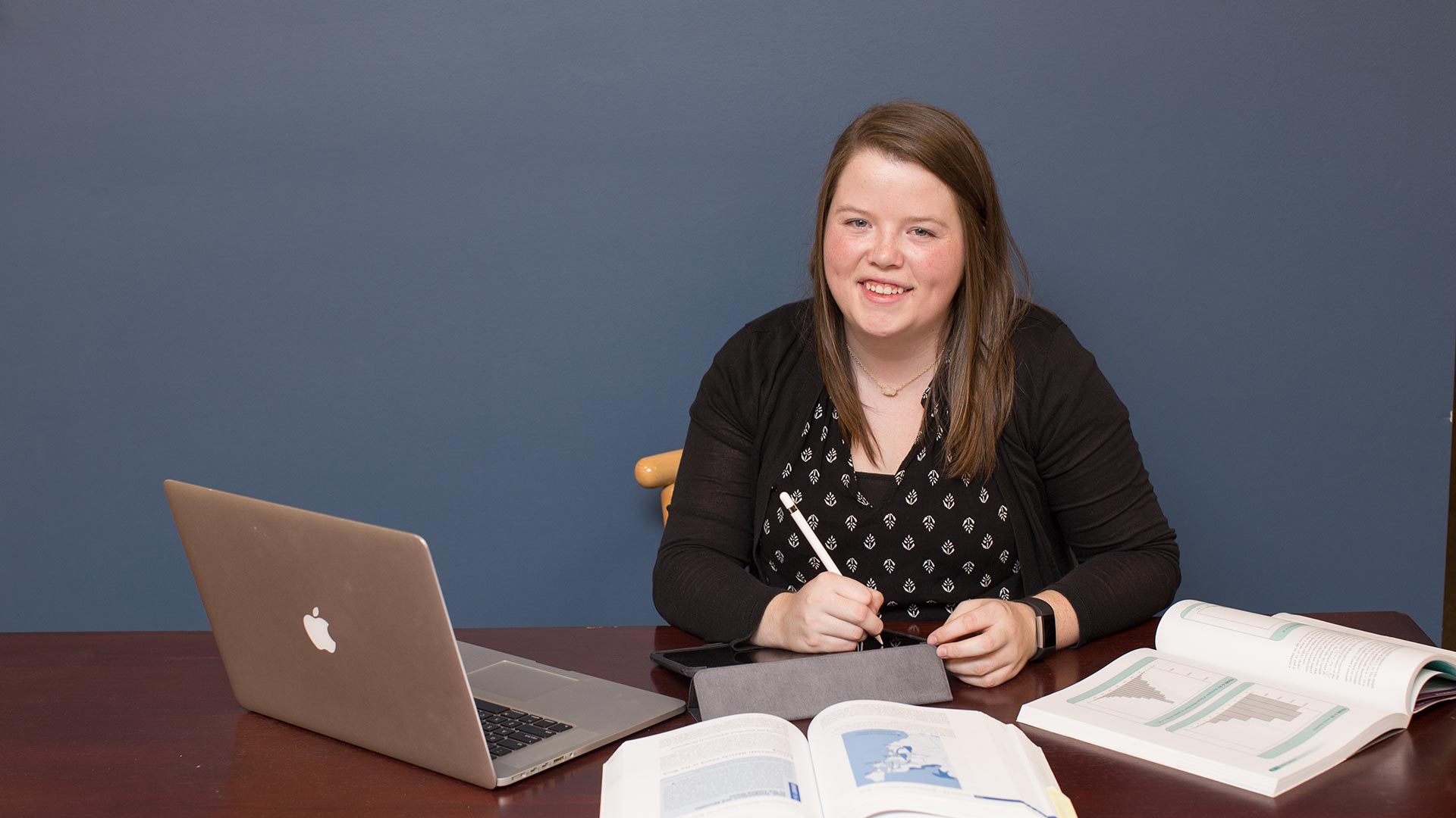 online masters student with computer and books